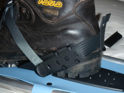 The snowshoes with a boot inside the straps from the back.